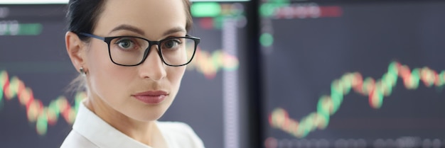 Portrait of businesswoman with glasses on background of electronic stock market analytics