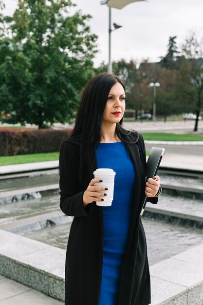 Portrait of a businesswoman with laptop and disposal cup