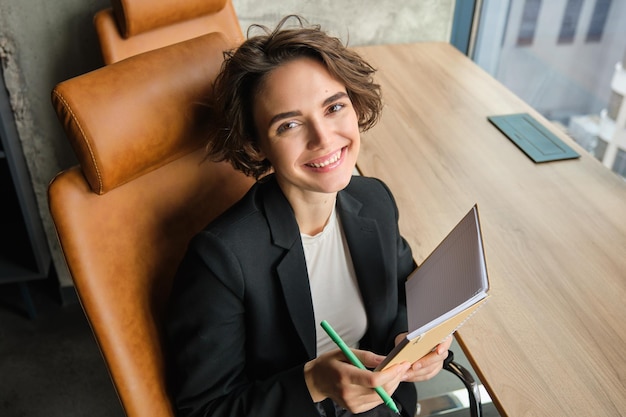 Free photo portrait of businesswoman working in her office making plans filling in her schedule in notebook or