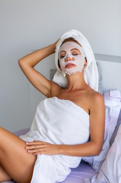 Portrait of calm caucasian pretty woman with a towel on head and mask