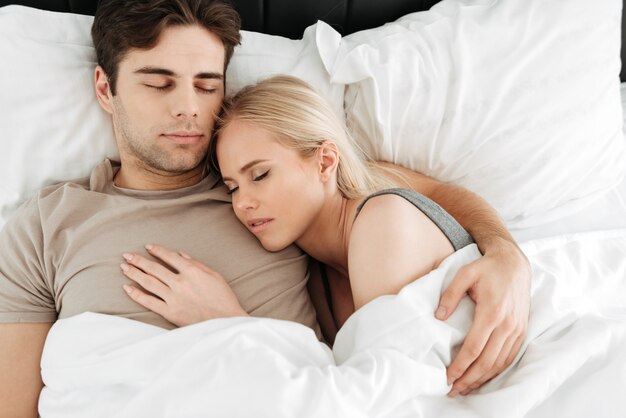 ベッドで寝ている穏やかなハンサムなカップルの肖像画