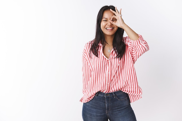 Free photo portrait of carefree amused and joyful    attractive asian woman  showing  okay sign on eye