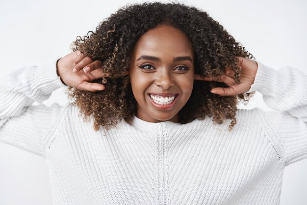 Portrait of carefree happy and joyful charismatic african american woman laughing and smiling happily close ears with index fingers and gazing delighted at front