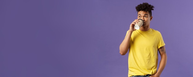 Free photo portrait of carefree young male student getting energy in morning from caffeine sipping coffee from