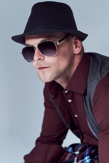 Free photo portrait of casual male dressed in a shirt, waistcoat and sunglasses over grey background.