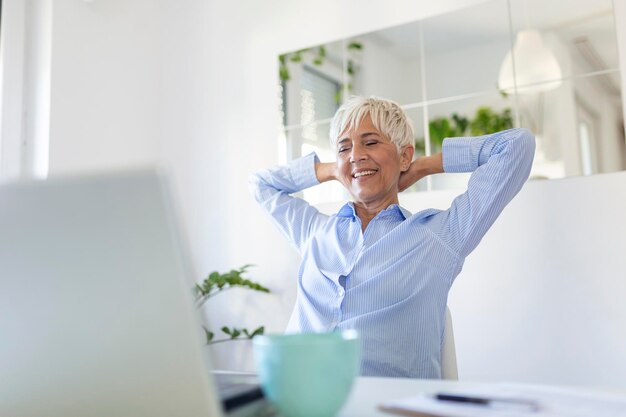 Portrait of casual woman using her laptop while sitting home office and working An attractive middle aged businesswoman sitting in front of laptop and managing her small business from home