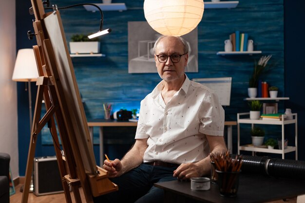 Portrait of caucasian elder artist sitting in artwork studio