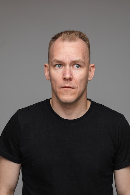 Portrait of caucasian man in black t-shirt looks aside isolated on grey wall