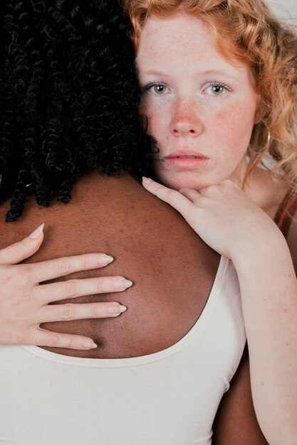 Portrait of a caucasian young woman hugging an african female