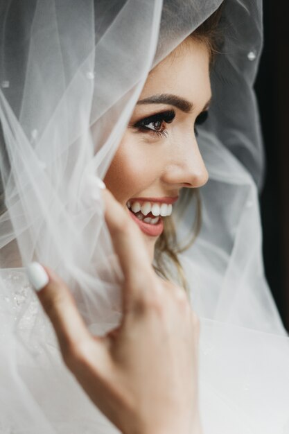 Portrait of charming bride enveloped in a veil 
