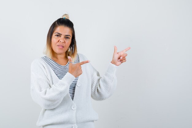 Tシャツ、カーディガンで右上隅を指して、賢明に見える魅力的な女性の肖像画