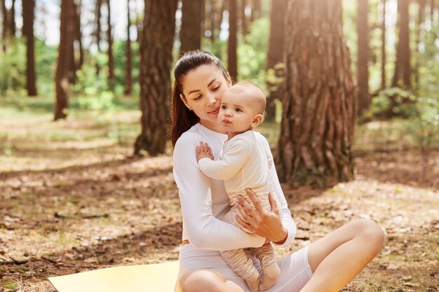 Portrait of charming little infant girl with mother in park