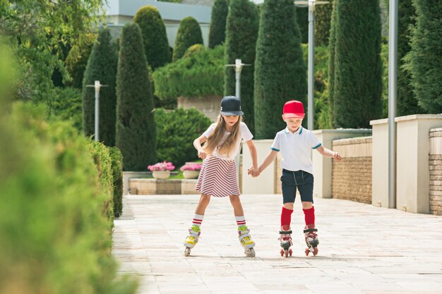 Portrait of a charming teenage couple skating together on roller skates at park.