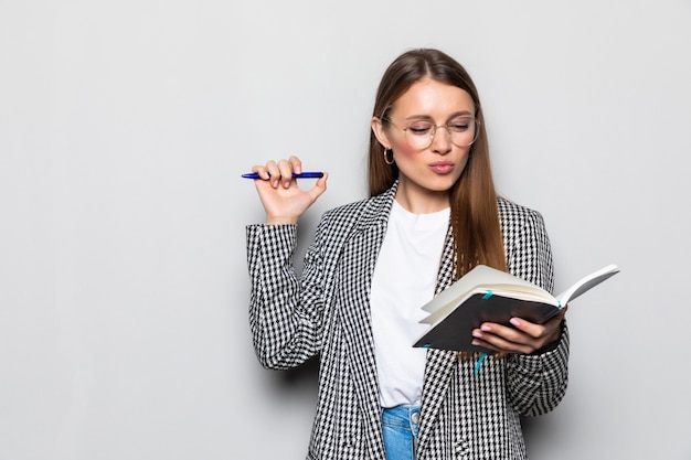 Portrait charming woman having notepad and pen in hands planning, expertising, analyzing isolated