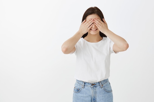 Portrait of charming young woman posing against white wall