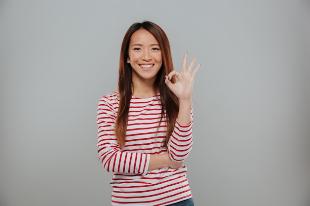 Портрет жизнерадостной азиатской женщины показывая одобренный жест