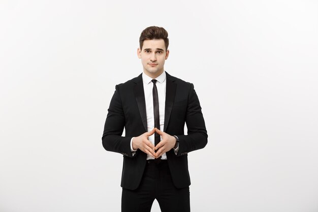 Portrait of cheerful, attractive, handsome businessman holding hands with confident face looking at camera standing over grey background