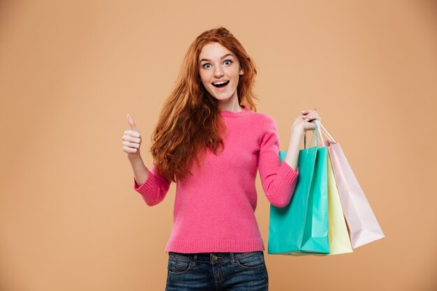 Portrait of a cheerful attractive redhead girl with shopping bags