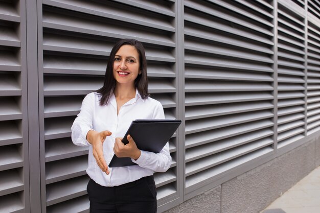 Portrait of cheerful businesswoman stretching hand for handshake