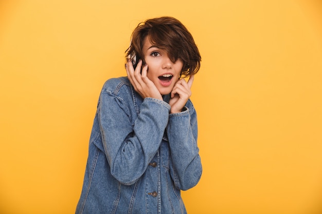 Il ritratto di una donna emozionante allegra si è vestito in giacca di jeans