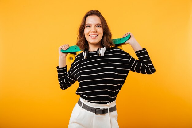 Portrait of a cheerful girl holding skateboard