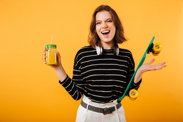 Portrait of a cheerful girl holding skateboard