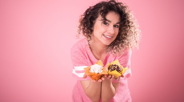 Portrait of a cheerful girl with cupcakes in her hands