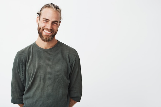 Portrait of cheerful handsome bearded guy with fashionable hairstyle smiling