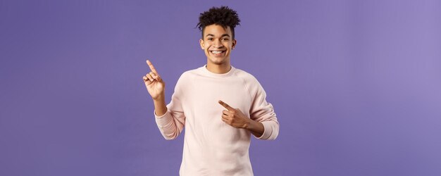 Portrait of cheerful healthy smiling man pointing fingers upper left corner recommending buy product