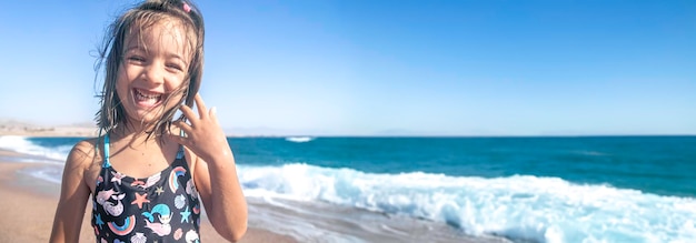 Free photo portrait of a cheerful little girl in a bathing suit by the sea on a sunny day