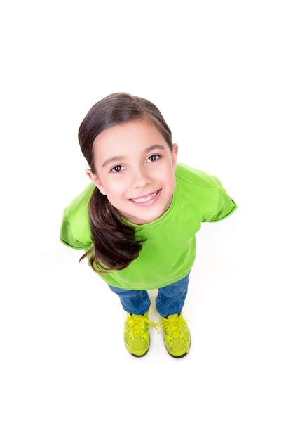Портрет веселой маленькой девочки, смотрящей в зеленой футболке. Вид сверху. Изолированные на белом фоне.