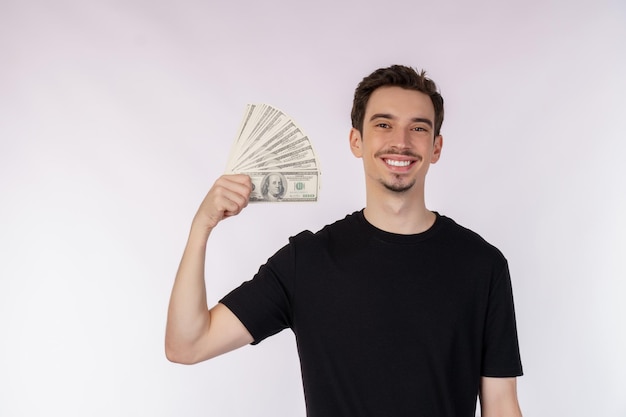 Portrait of a cheerful man holding dollar bills over white background