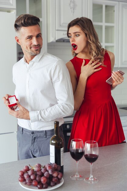 Portrait of a cheerful man proposing to his shocked girlfriend