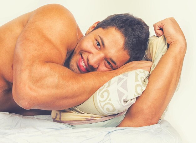 Portrait of a cheerful man relaxing in his bedroom lying on his bed