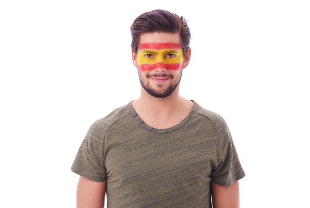 Portrait of cheerful man with spanish flag on face