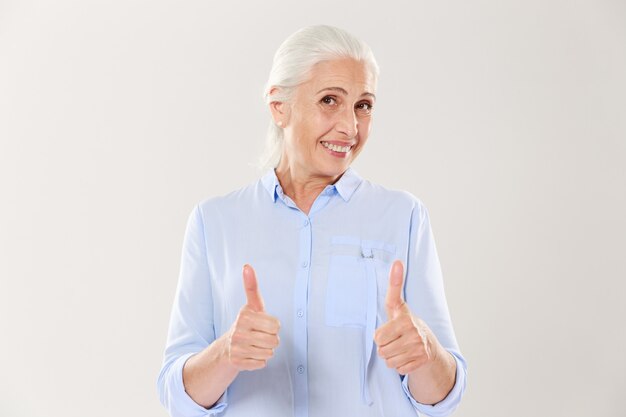 Портрет жизнерадостная старуха в синей рубашке, показывает палец вверх жест