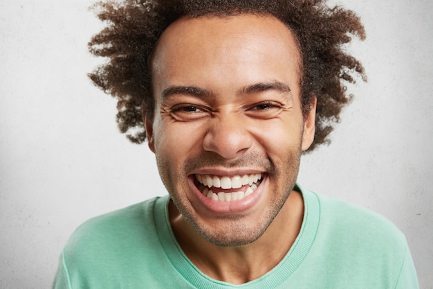 Free photo portrait of cheerful overjoyed male with bushy hairdo, smiles happily,