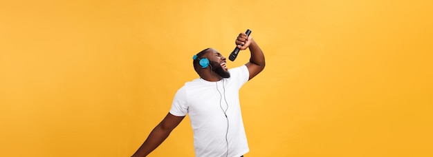 Portrait of cheerful positive chic handsome african man holding microphone and having headphones on