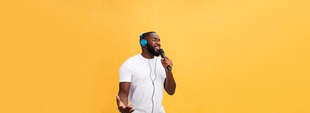 Free photo portrait of cheerful positive chic handsome african man holding microphone and having headphones on