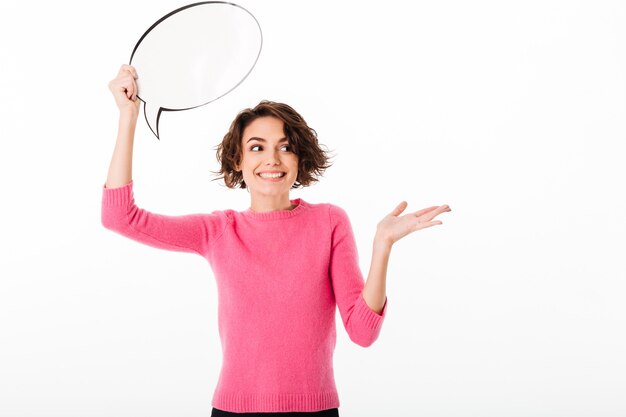 Portrait of a cheerful pretty girl holding blank speech bubble