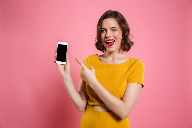 Portrait of a cheerful pretty woman pointing finger at blank