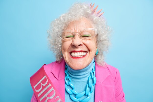 쾌활한 고위 여자의 초상화 웃음, 눈을 감고 미소는 광범위하게 흰색 완벽한 치아가 파티에 자유 시간을 보내는 것을 즐긴다. 여성 은퇴 연령 개념