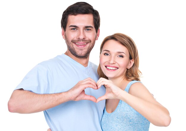 Портрет веселой улыбающейся пары, стоящей вместе, показывает сердце руки - изолированные