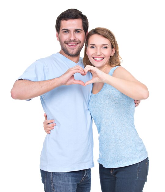 Портрет веселой улыбающейся пары, стоящей вместе, показывает сердце руки - изолированные