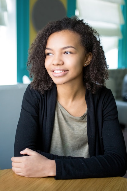 Portrait of cheerful teenage girl sitting in cafe