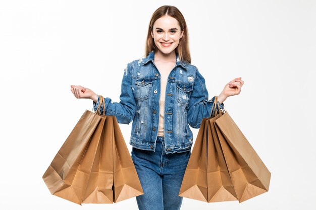 Portrait of a cheerful woman holding shopping bagsisolated over gray wall