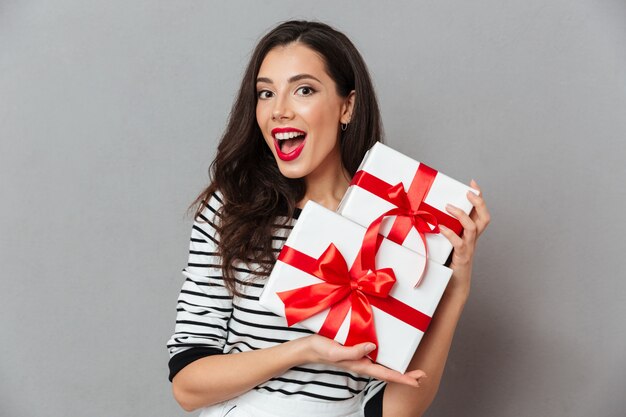 Portrait of a cheerful woman holding stack of gift boxes