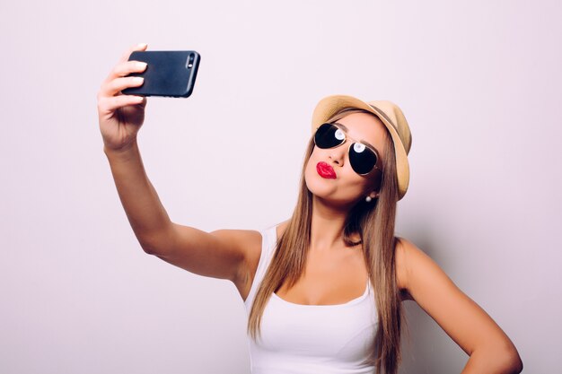 Portrait of a cheerful woman making selfie photo over gray wall