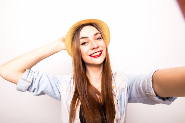 Portrait of a cheerful woman making selfie photo over gray