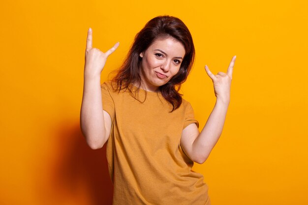 Portrait of cheerful woman showing rock sign with hands